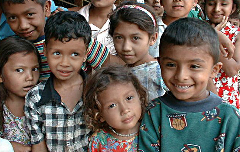 Children gathered outside their school posing for the camera.