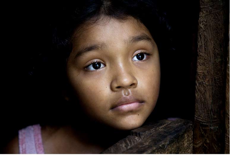 A little girl in Honduras looks out of her home.