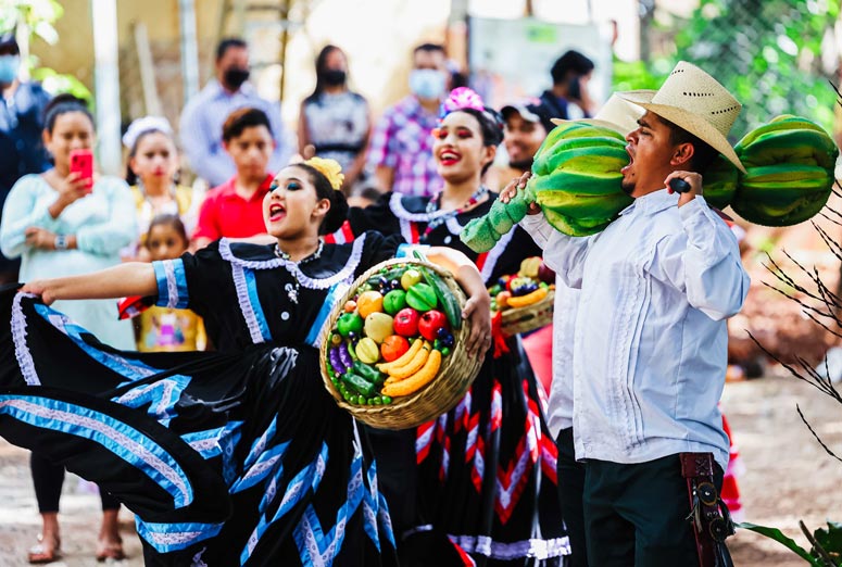 Dancers in festive cultural clothing at outdoor festival event in Honduras.